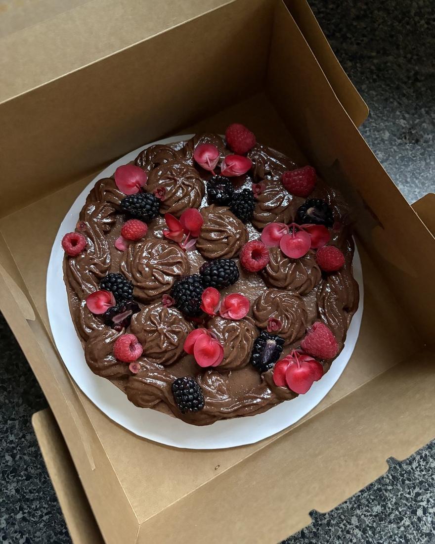 Chocolate cake with piped ganache, raspberries and blackberries in its box