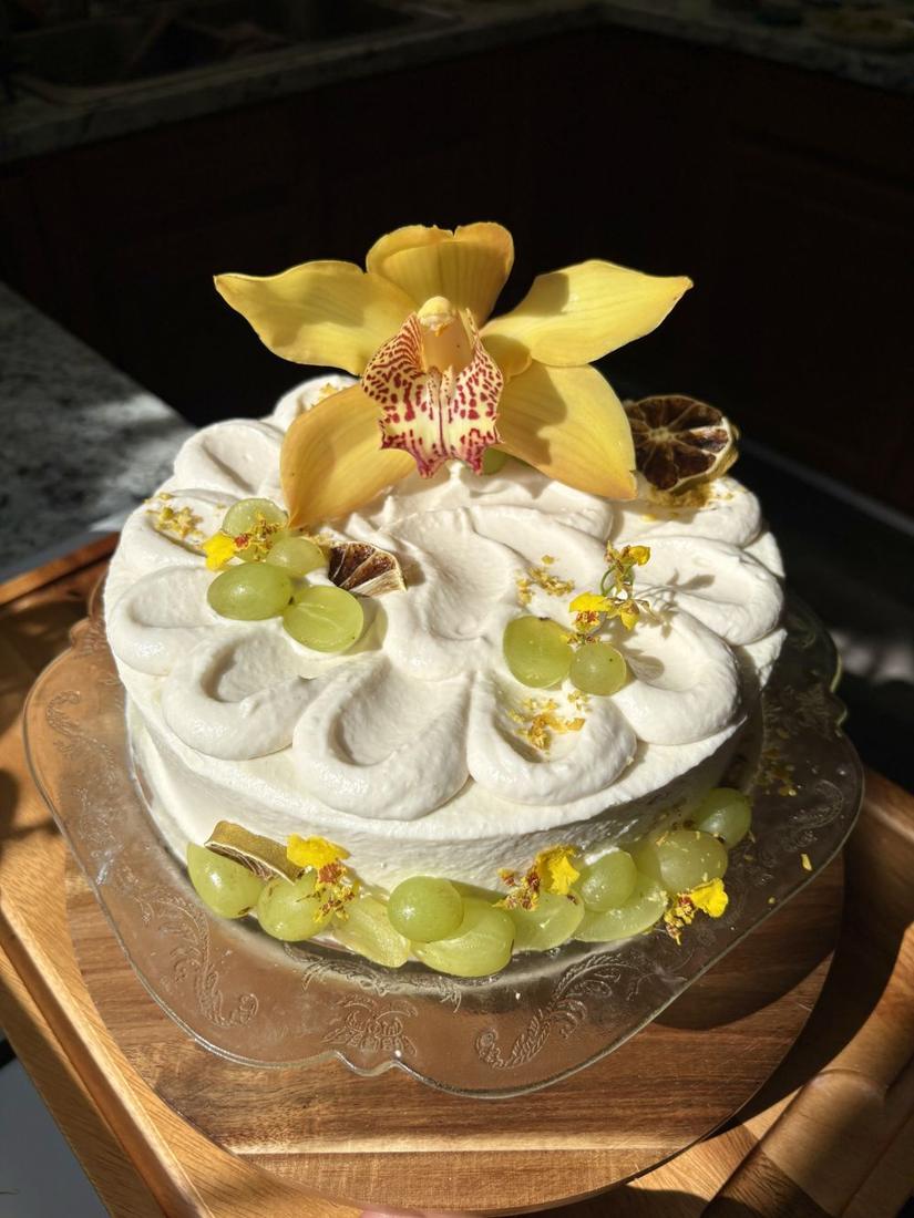 White cake with a yellow orchid and green grapes