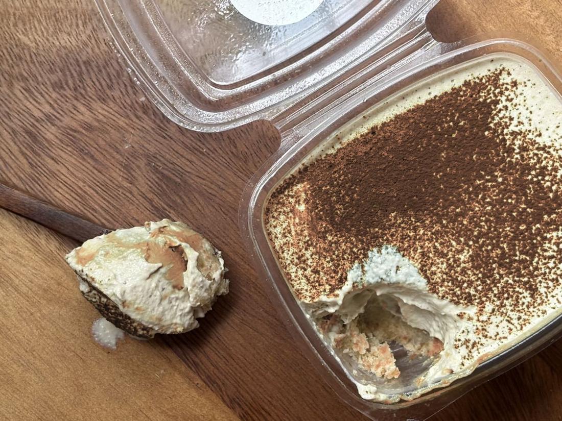 Tiramisu dusted with cocoa, with a spoonful taken