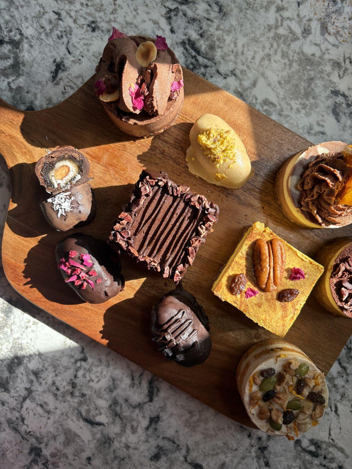 A wooden board with Flöra baby cakes, date bonbons and bites in the sun